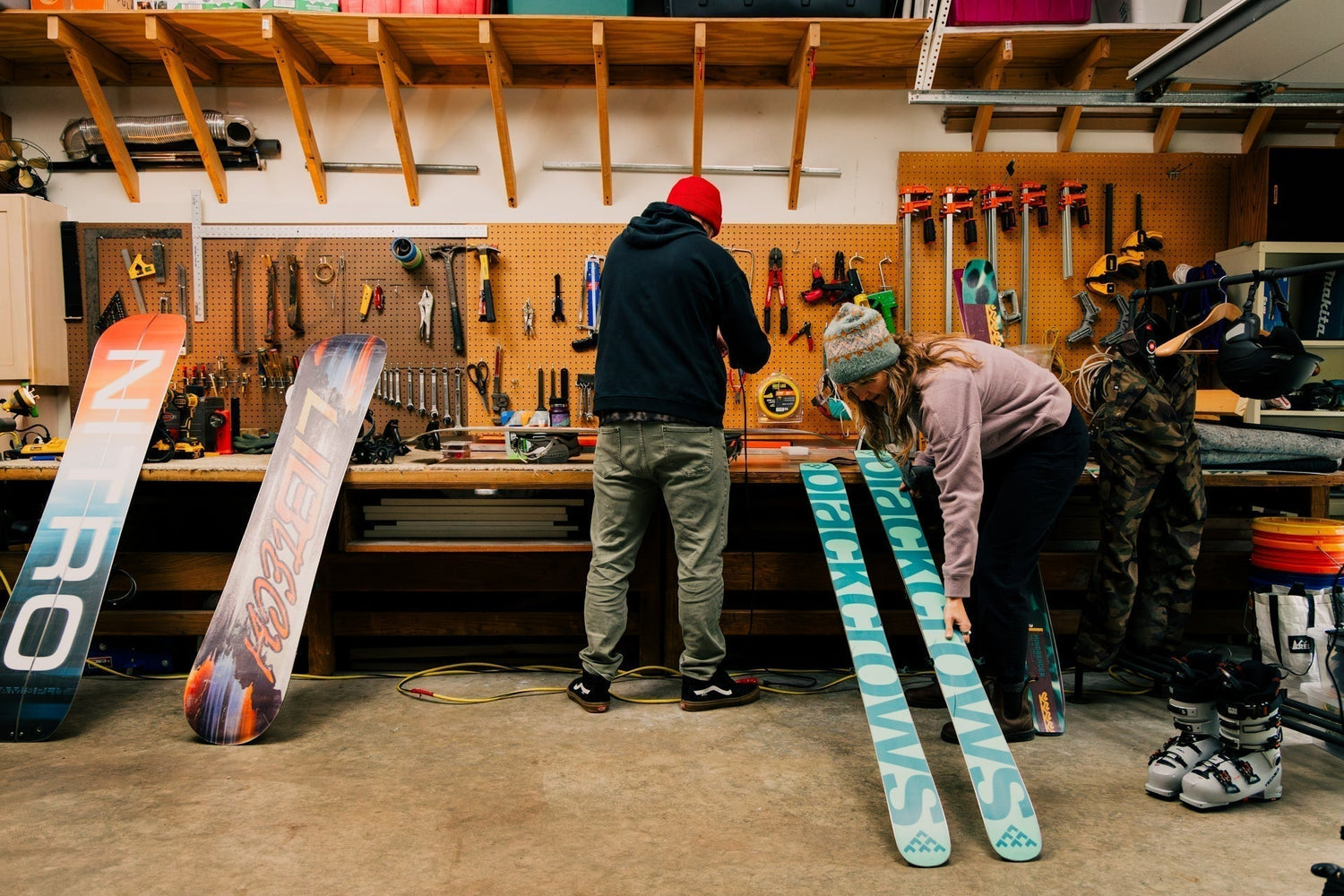 Couple Waxing snowboards in a wooden garage workshop