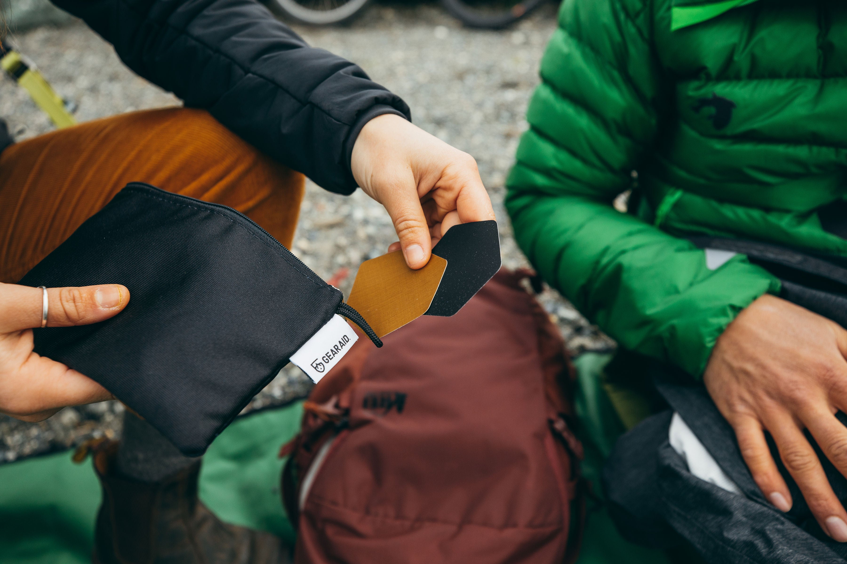 Person pulling two Tenacious Tape Hex Patches out of a small bag to make a repair