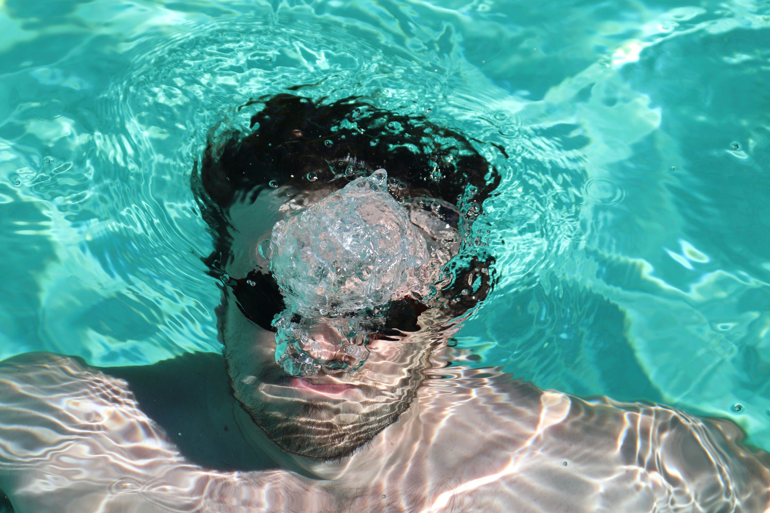 Person wearing swim goggles under the water in a pool