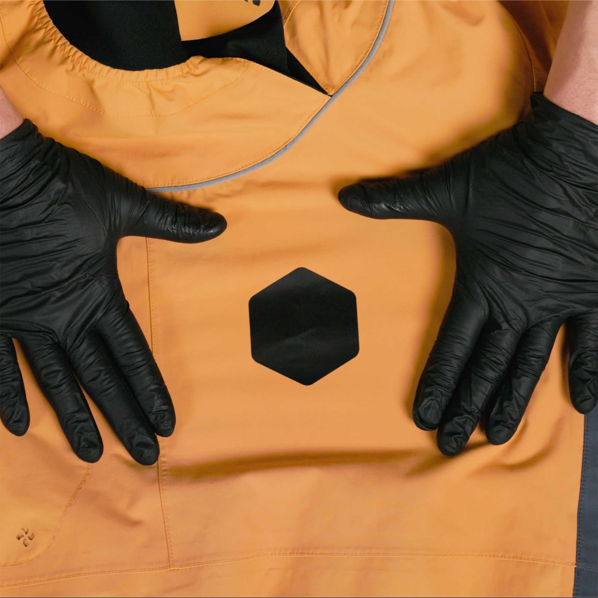 Hands wearing black gloves and displaying a finished repair on a paddling jacket