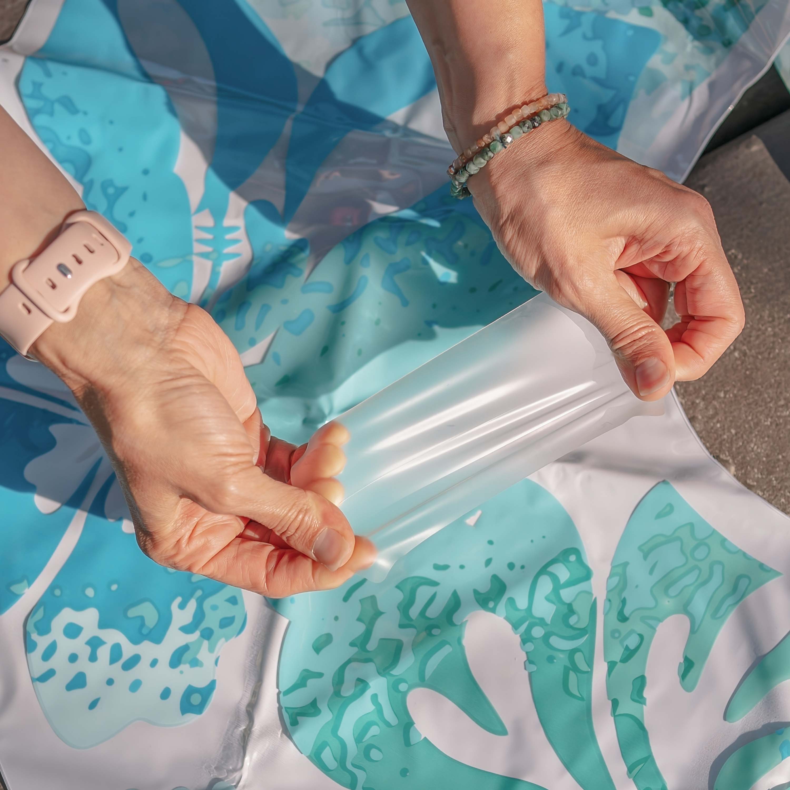 Close-up of hands holding a clear plastic bag with a blue and white patterned surface underneath