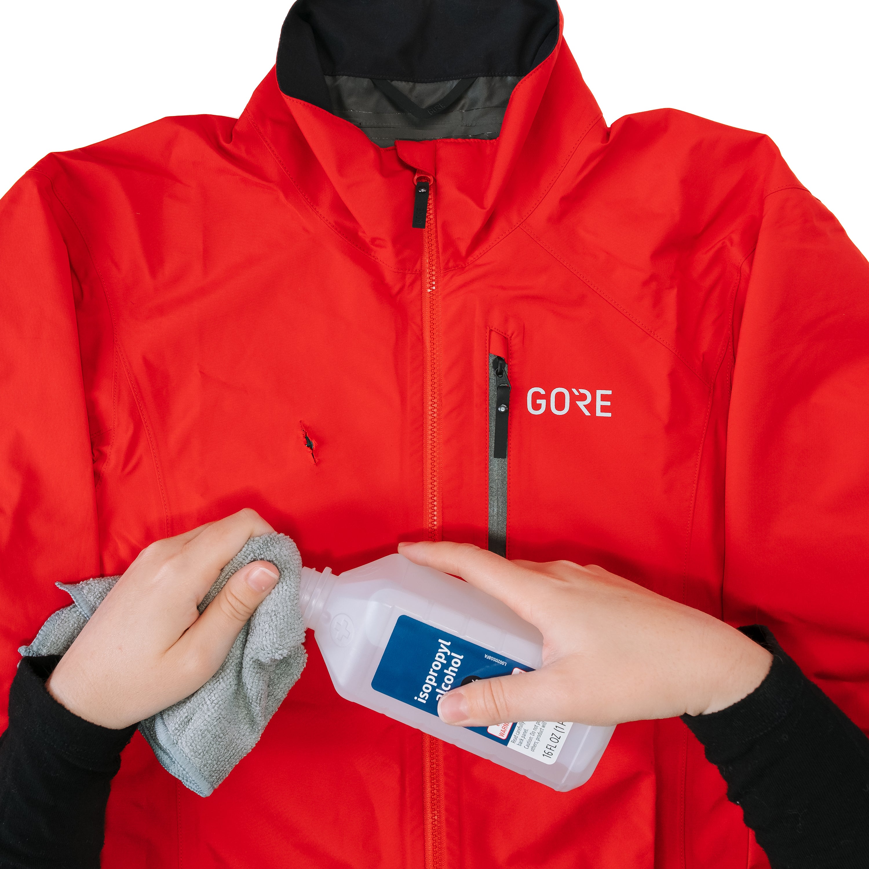 Person applying a product to a red jacket with 'GORE' branding.