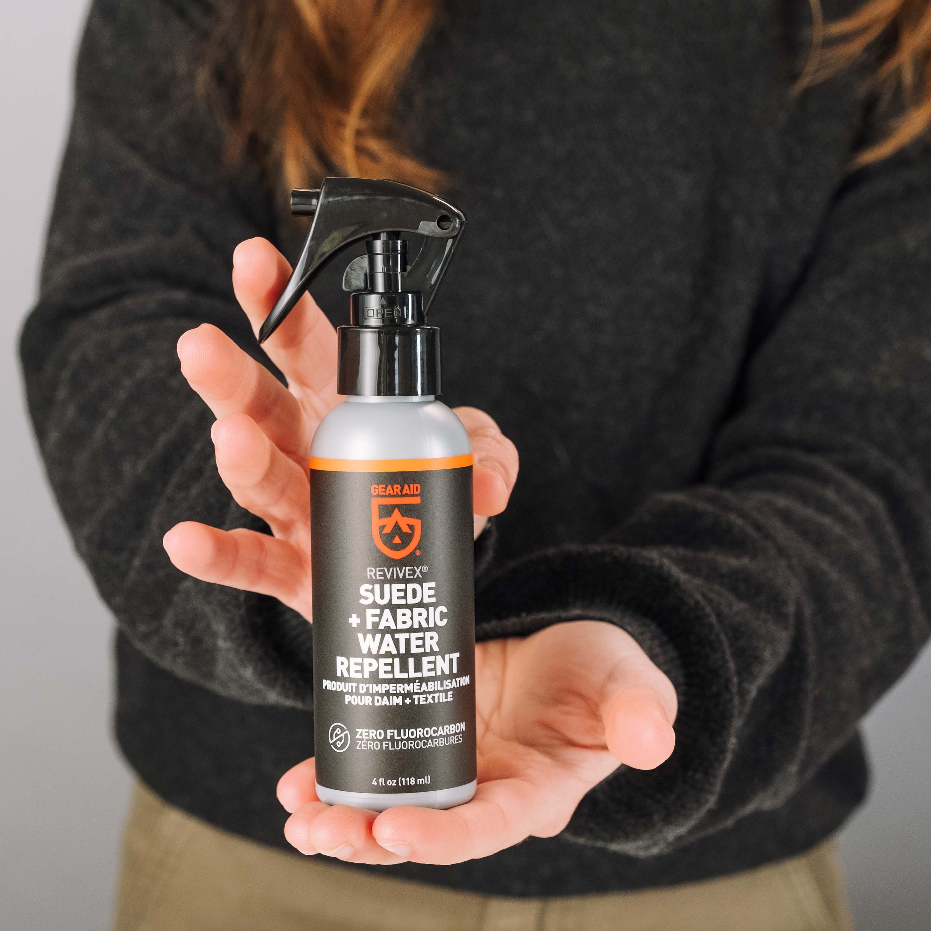Person holding a bottle of suede and fabric water repellent spray.