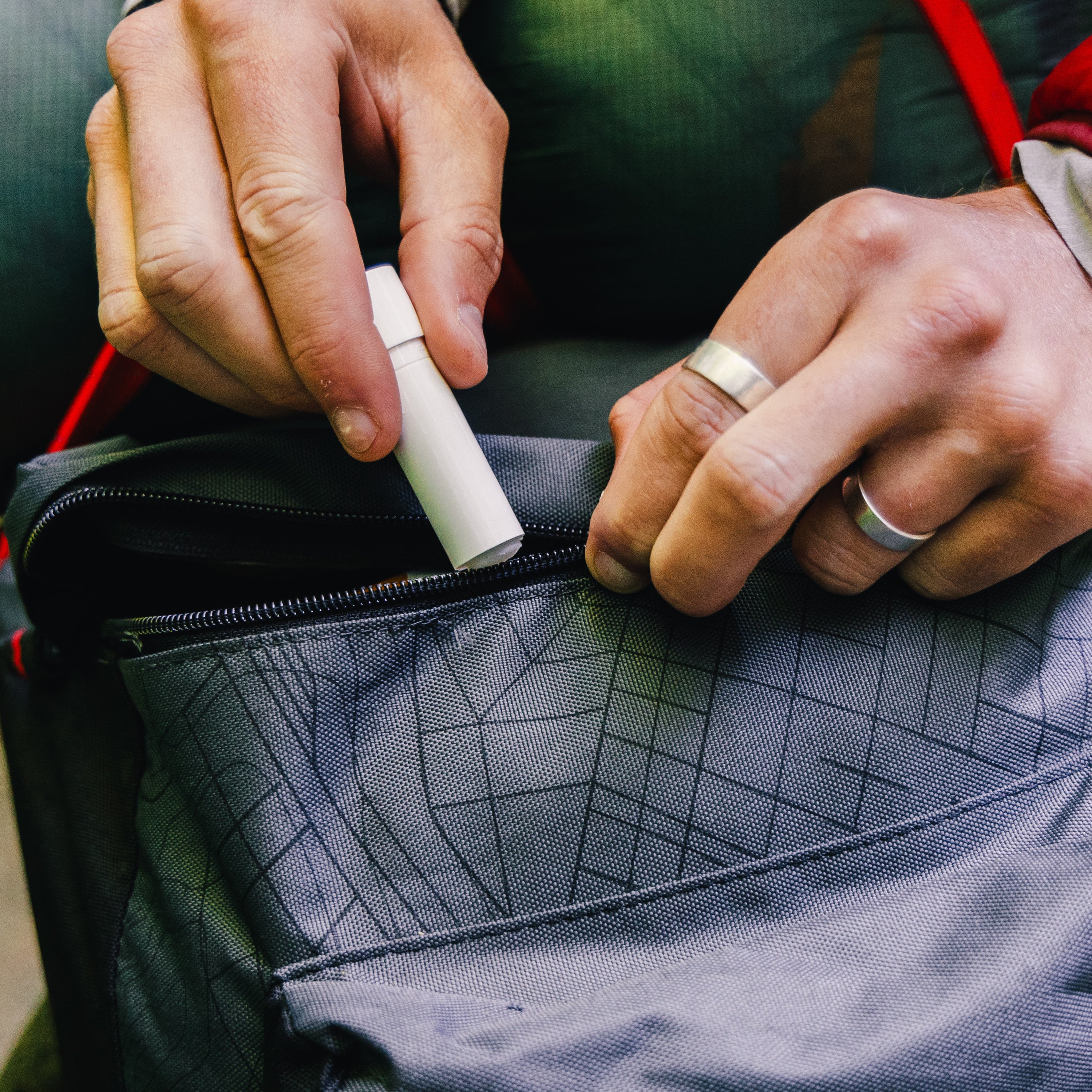 Person opening a backpack with Zipper Lubricant in hand.