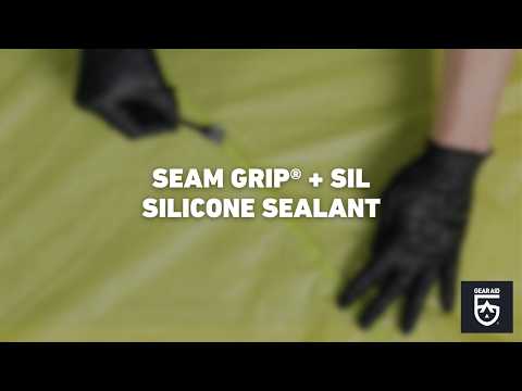 Blurred video cover showing gloved hands working with light green tent fabric on a tabletop, with the title “SEAM GRIP® + SIL SILICONE SEALANT” centered and the Gear Aid logo in the bottom-right corner.