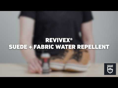 Blurred video cover showing a pair of suede shoes beside a bottle of treatment product on a tabletop, with the title “REVIVEX® SUEDE + FABRIC WATER REPELLENT” centered and the Gear Aid logo in the bottom-right corner.