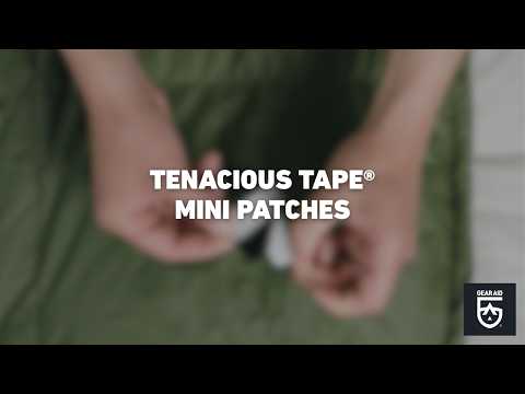 Blurred video cover showing hands peeling a small repair patch from its backing sheet above green outdoor fabric, with the title “TENACIOUS TAPE® MINI PATCHES” centered and the Gear Aid logo in the bottom-right corner.