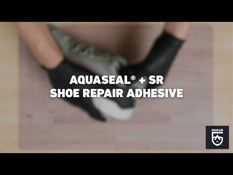 Blurred video cover showing gloved hands repairing a shoe on a work surface, with the title “AQUASEAL® + SR SHOE REPAIR ADHESIVE” centered and the Gear Aid logo in the bottom-right corner.