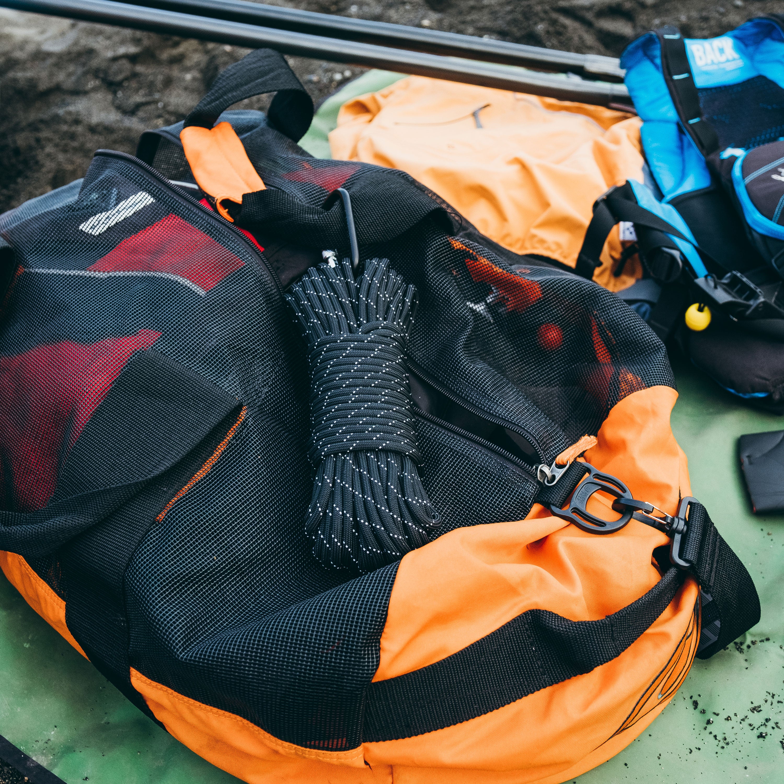 Paracord in Black Reflective Color clipped with a black carabiner to a mesh river bag, kayak and kayak gear in the background