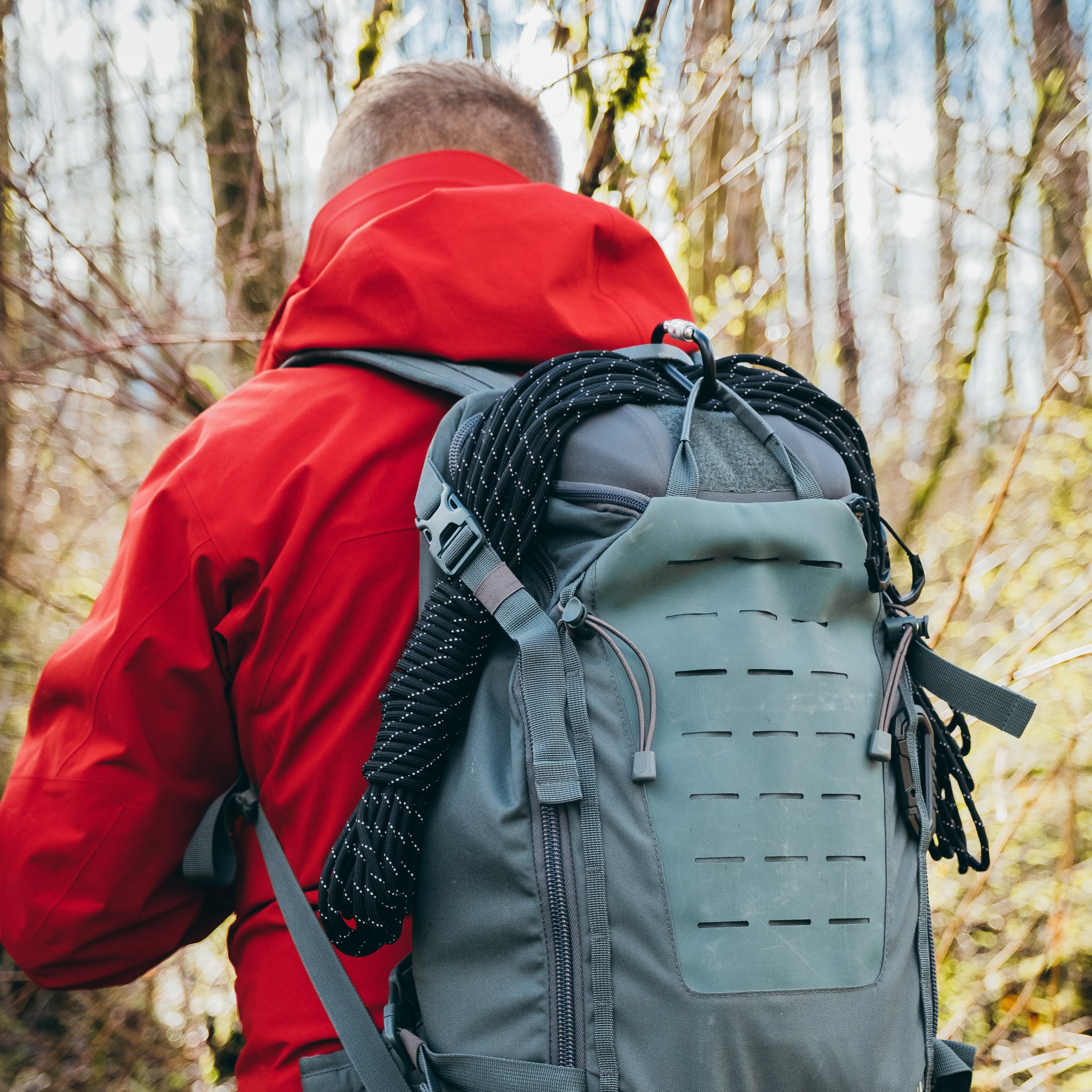 Paracord in Black Reflective Colordrapped over a day pack on back of person walking away into the woods