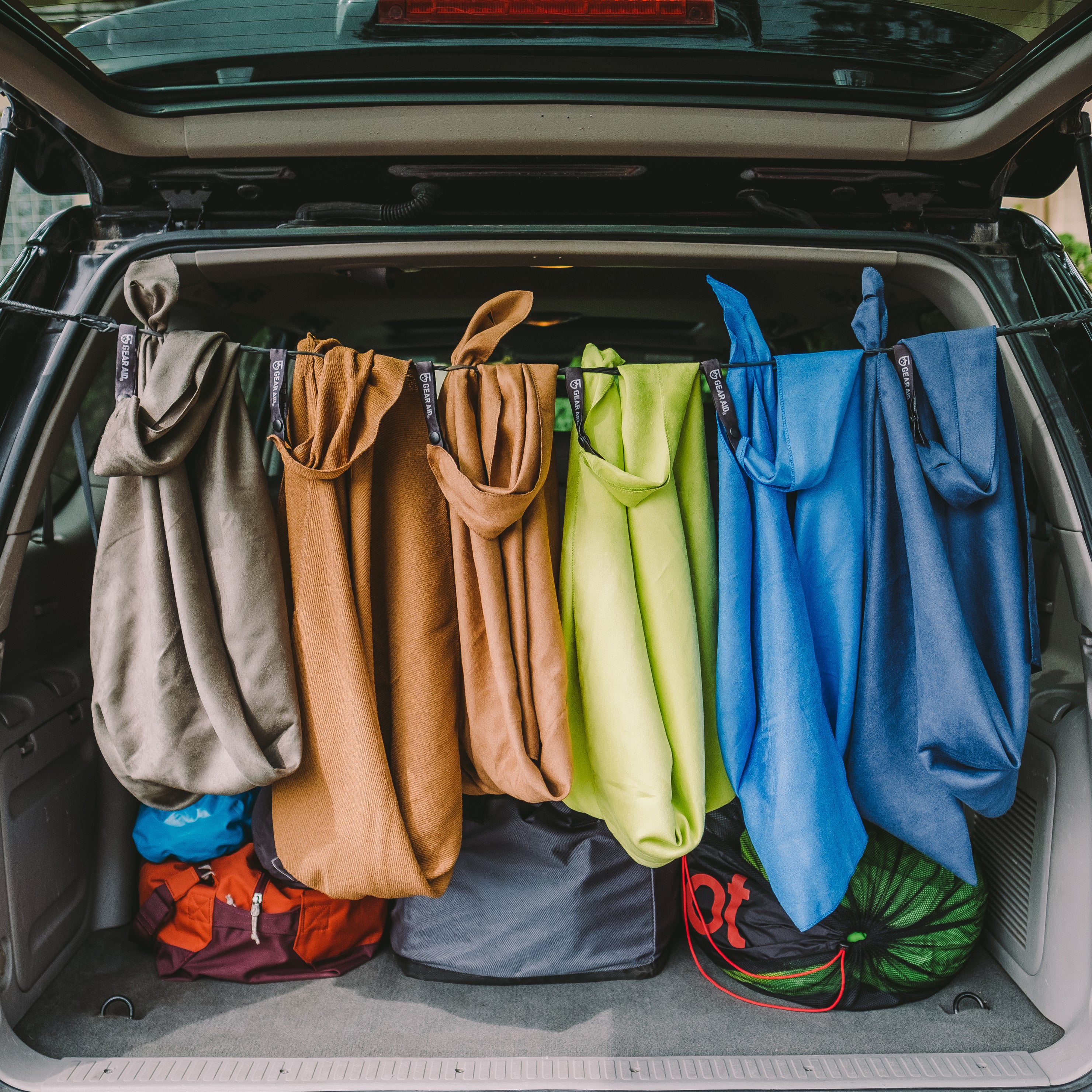 Microfiber towels hanging up to dry on a line across the open hatch back of a vehicle