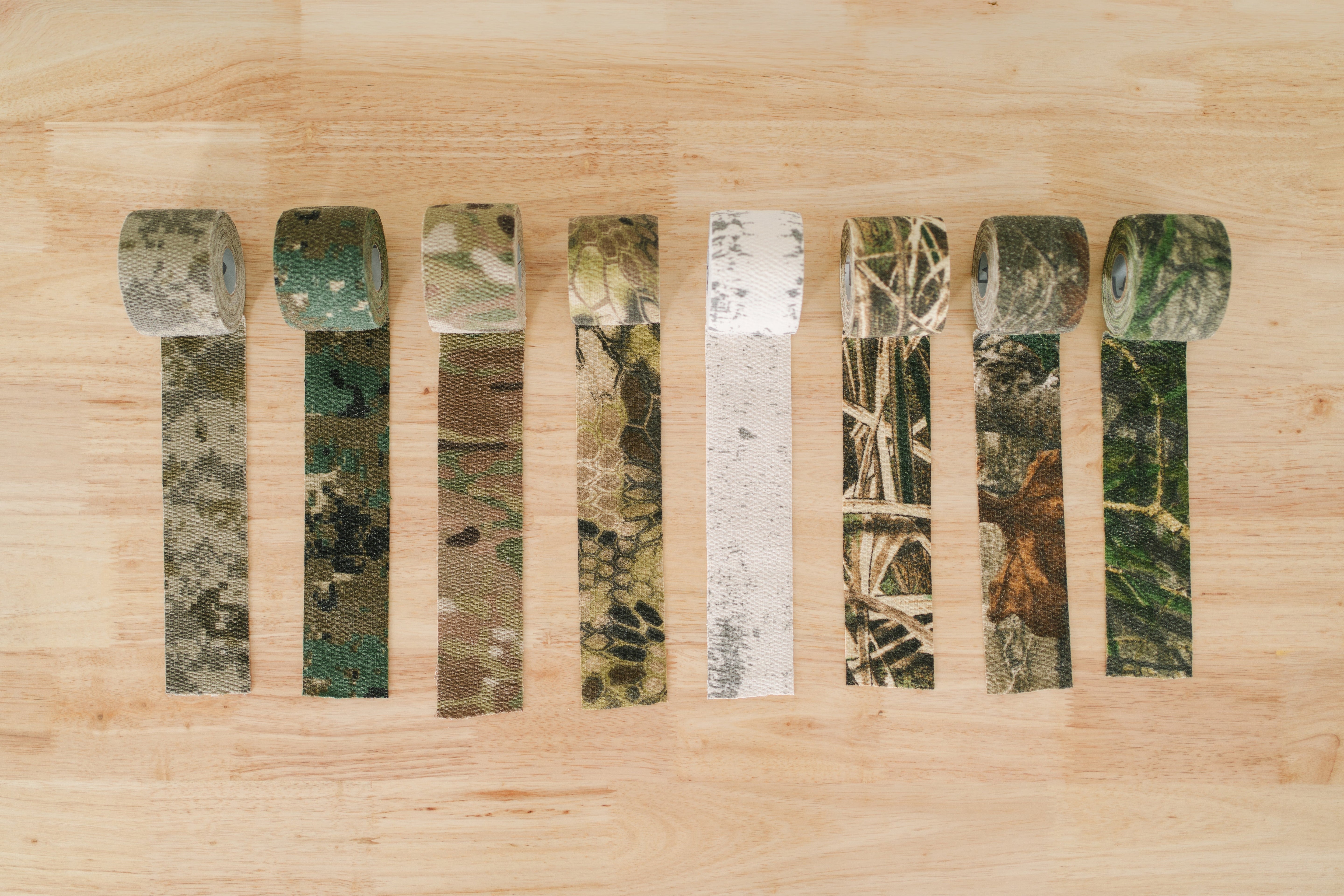Line up of all GEAR AID Camo Form concealment wraps on wood table