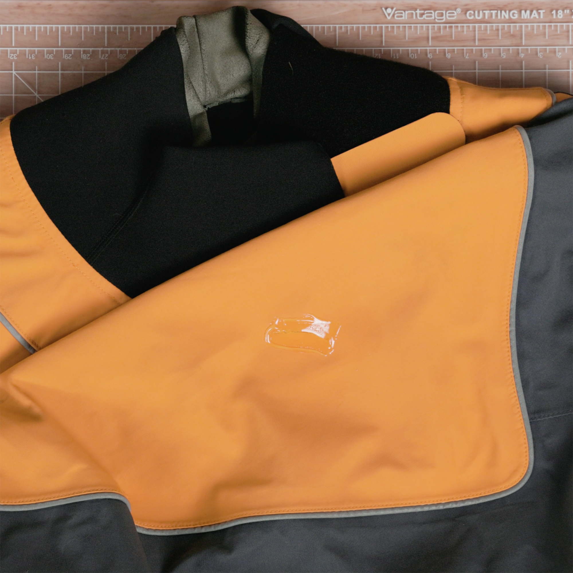 A small amount of Aquaseal FD smoothed onto an orange, gray, and black drysuit top