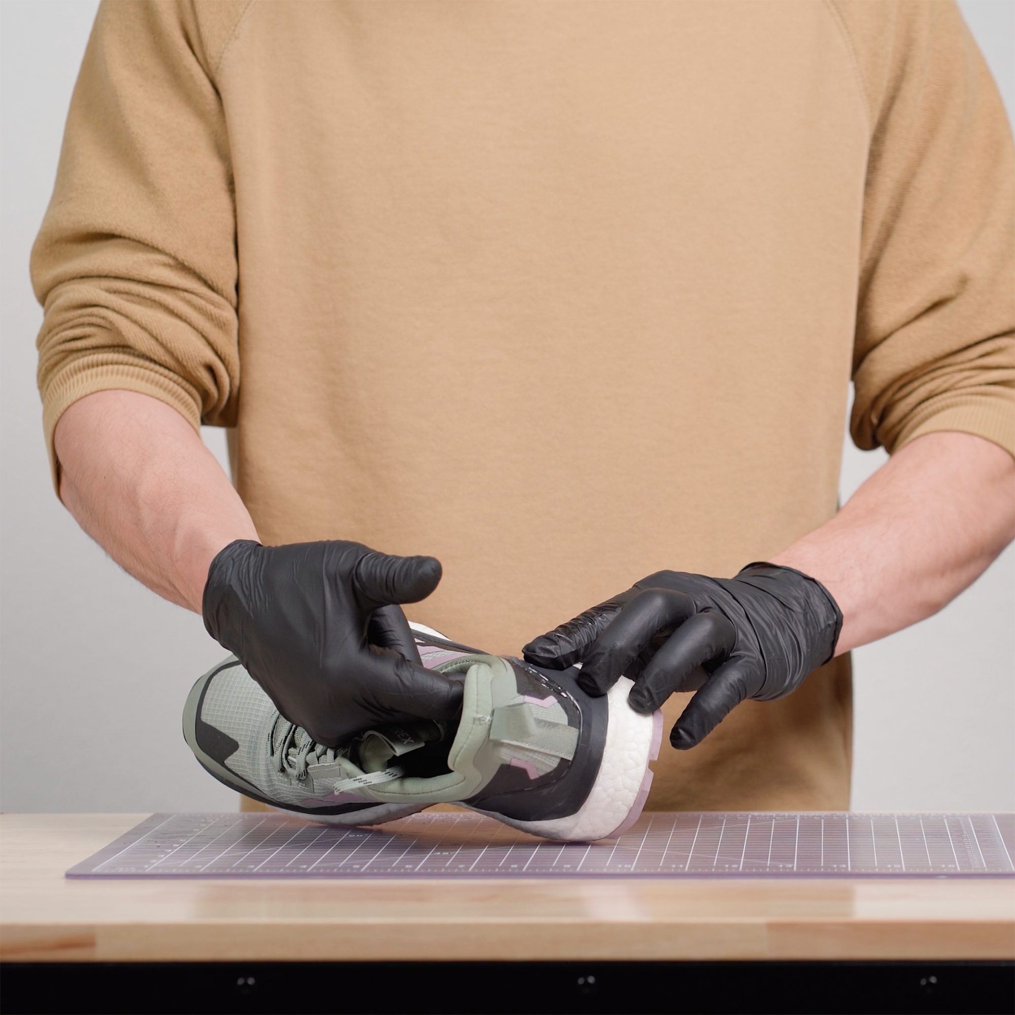 Person wearing black gloves and pressing the repaired part of a trail runner together so the pieces can cure together