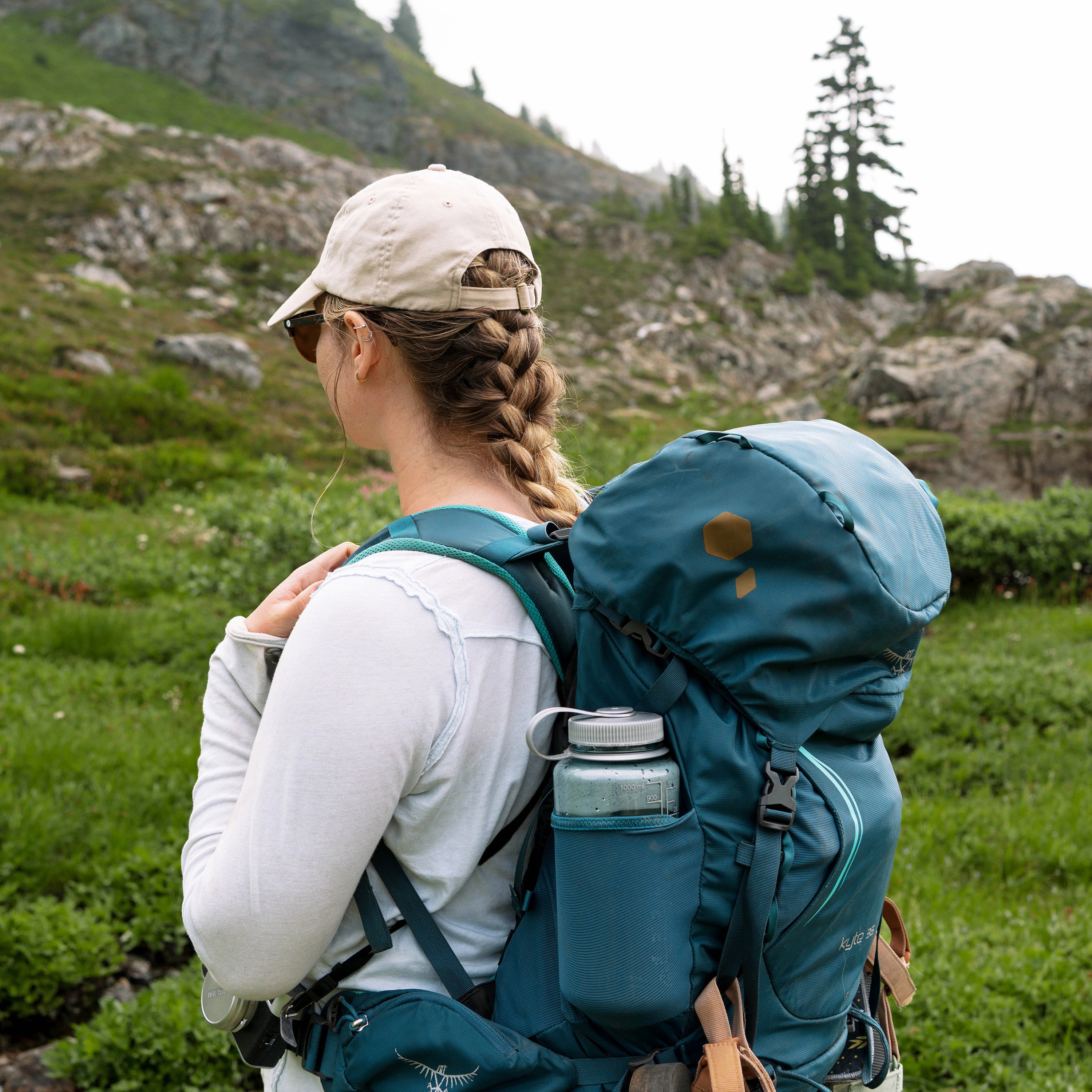 Person with a large blue backpack with patches hiking in a mountainous area