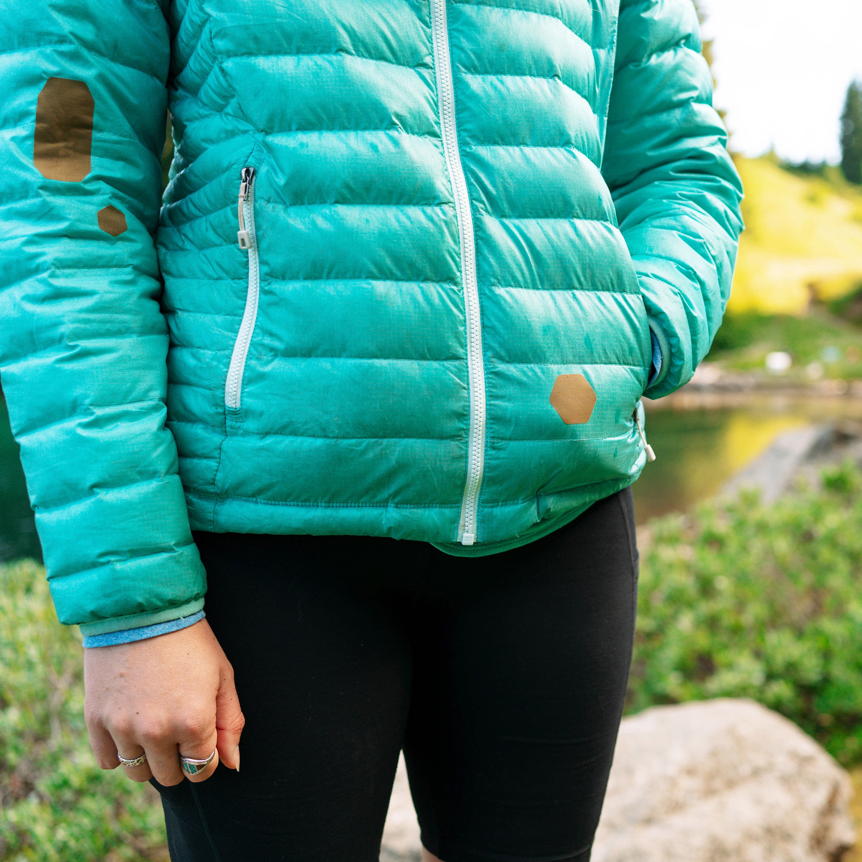 Person wearing a teal puffer jacket outdoors with a natural background
