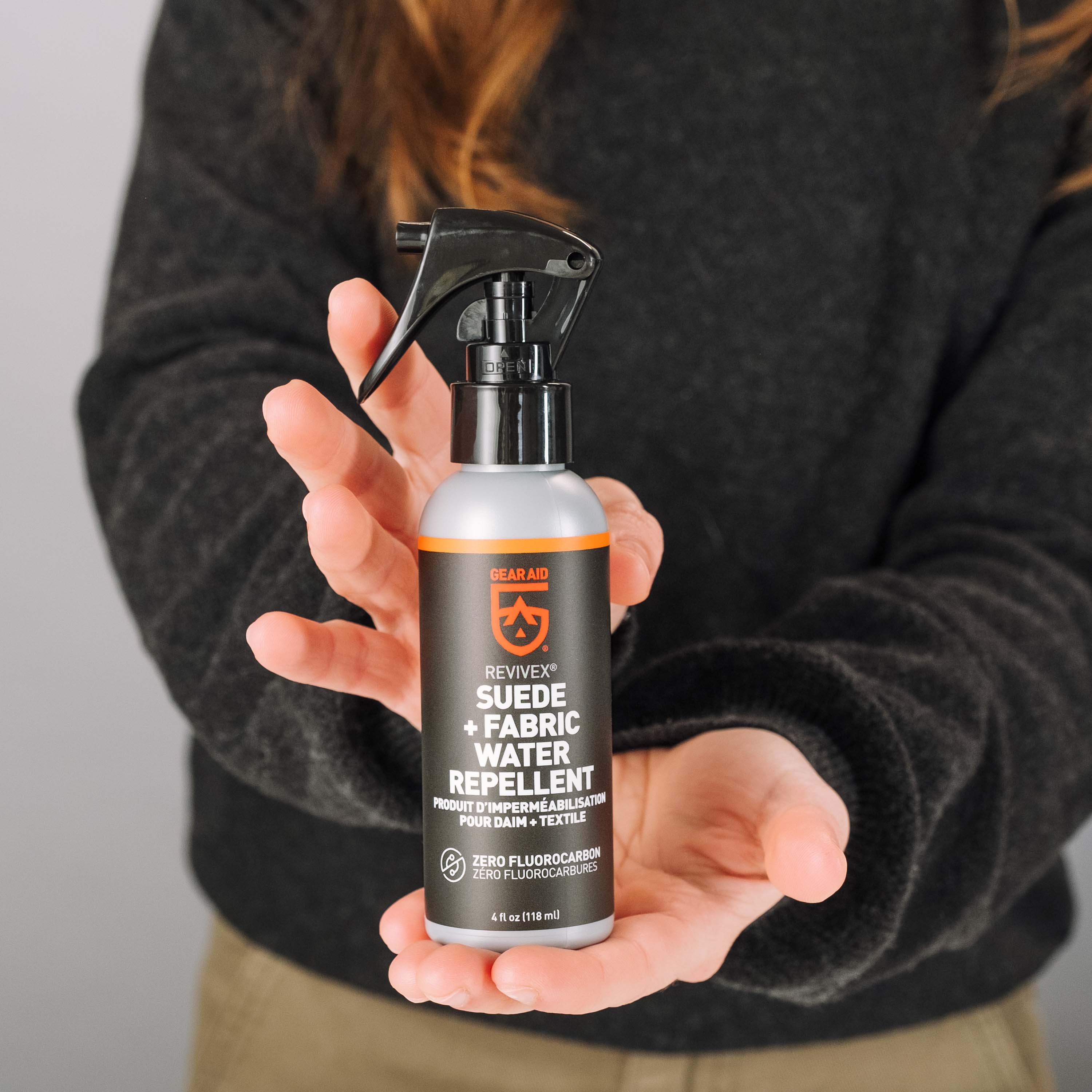 Person holding a suede fabric water repellent spray bottle