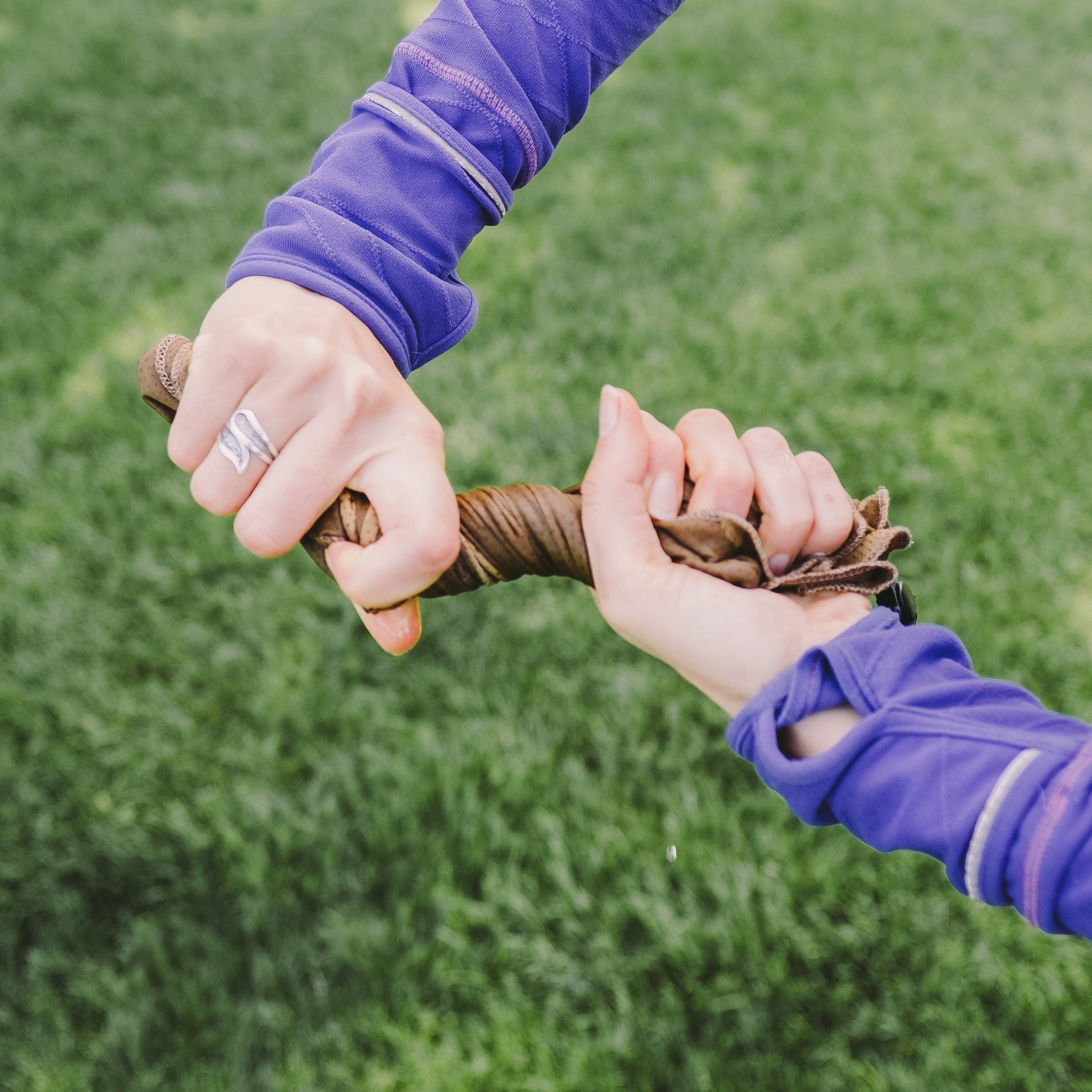 Two pairs of hands wringing out a washcloth against a grassy background.