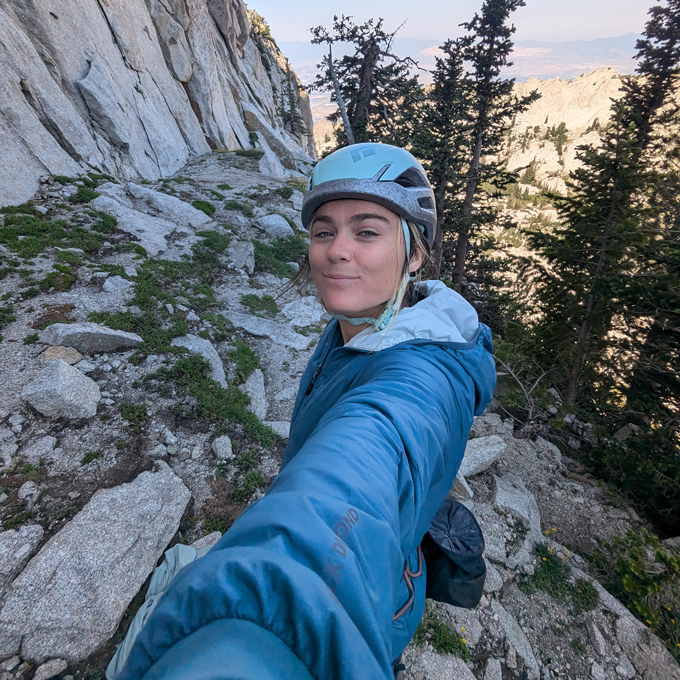 Person in blue jacket and helmet on a mountain trail.