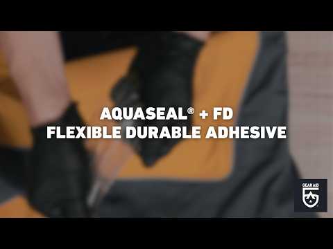 Blurred video cover showing gloved hands repairing orange outdoor gear with adhesive, with the title “AQUASEAL® + FD FLEXIBLE DURABLE ADHESIVE” centered and the Gear Aid logo in the bottom-right corner.