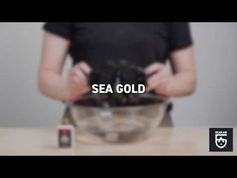 Blurred video cover showing a person holding a diving mask above a metal bowl, with a small product bottle on the table, the title “SEA GOLD” centered, and the Gear Aid logo in the bottom-right corner.