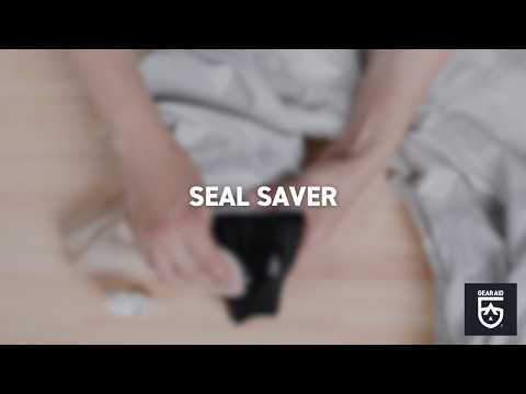 Blurred video cover showing hands applying conditioner to a black wetsuit seal on a tabletop, with the title “SEAL SAVER” centered and the Gear Aid logo in the bottom-right corner.