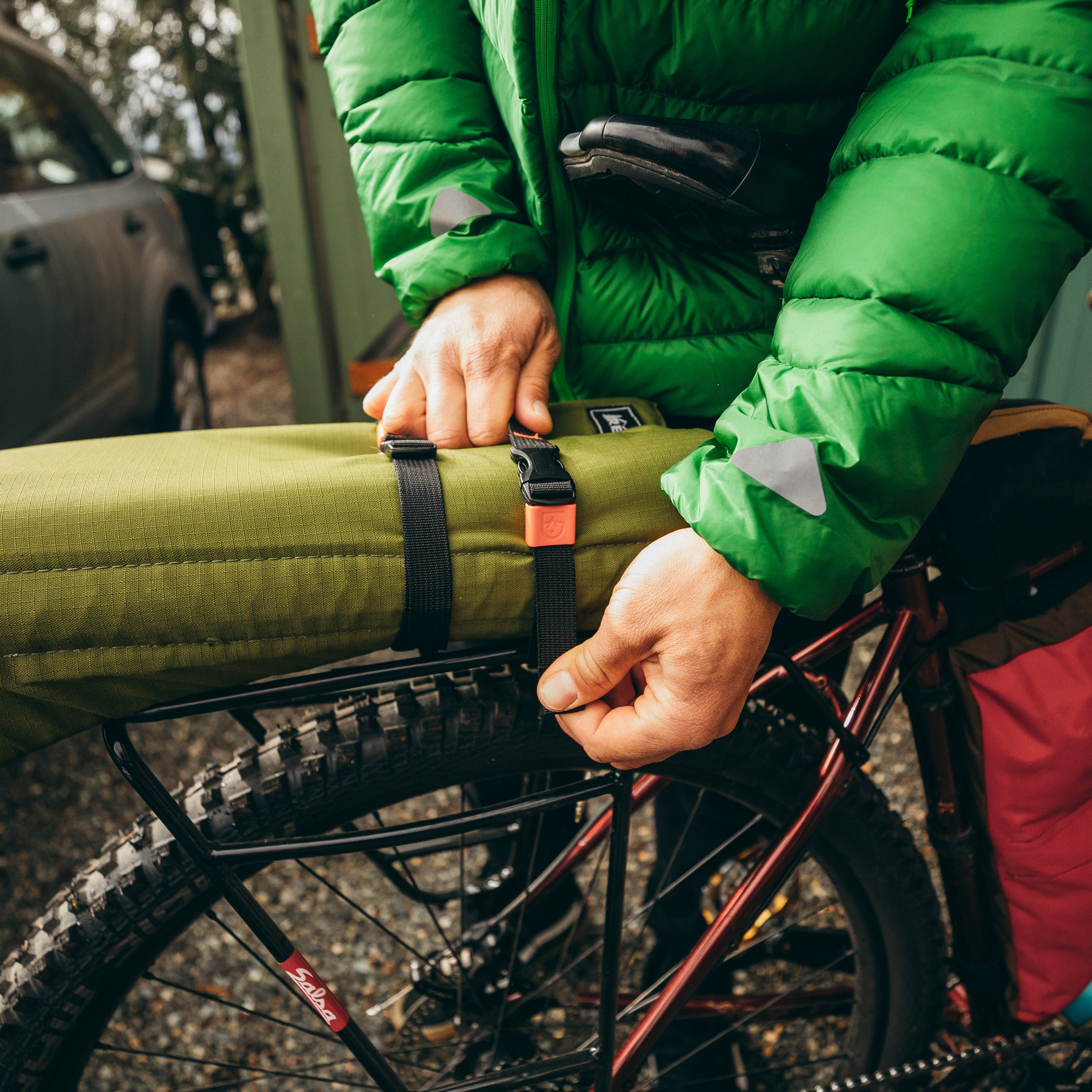 Person strapping some outdoor gear onto a bike rack using Utility Strap