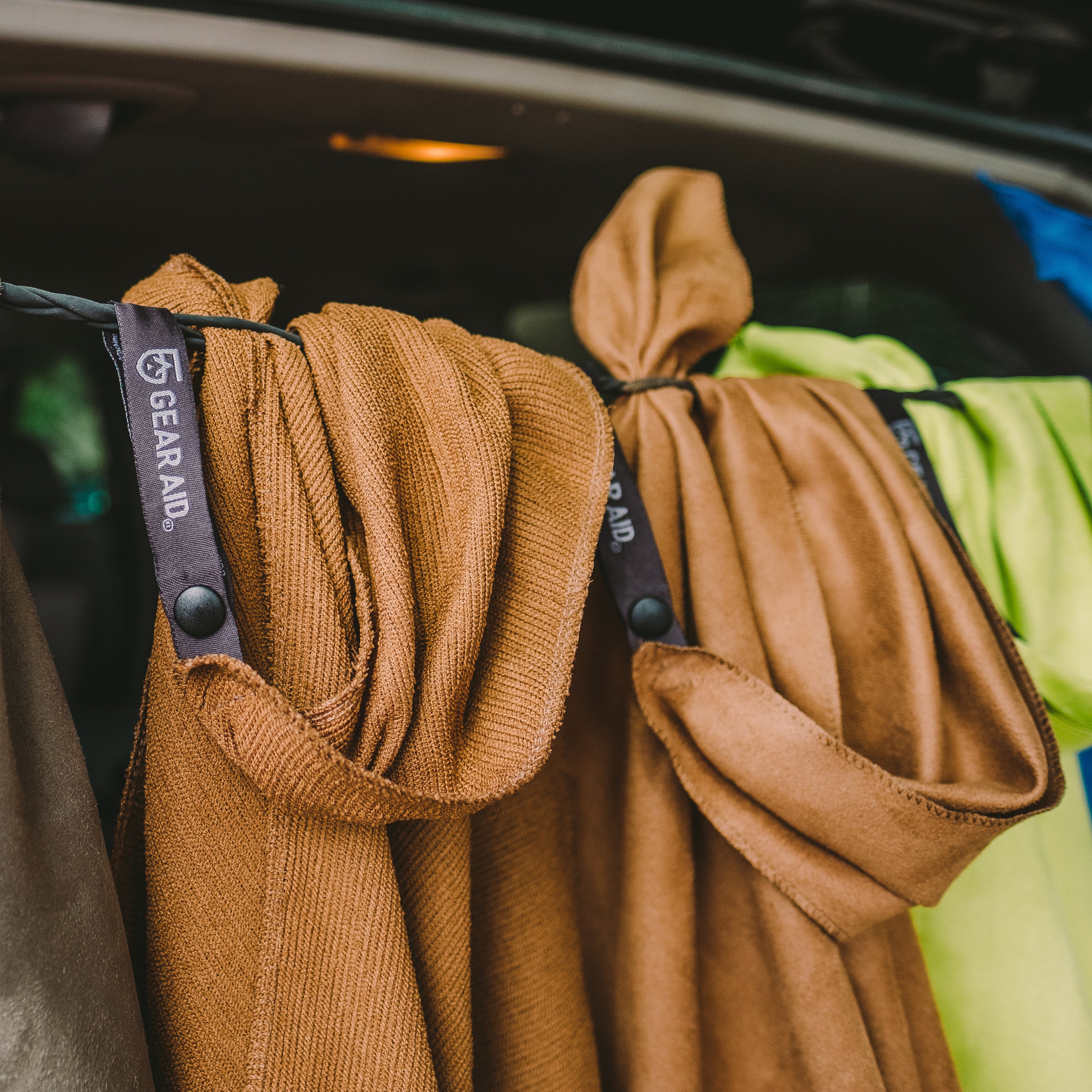 Multiple microfiber towels attached to a line across the back of a vehicle with hatch open.